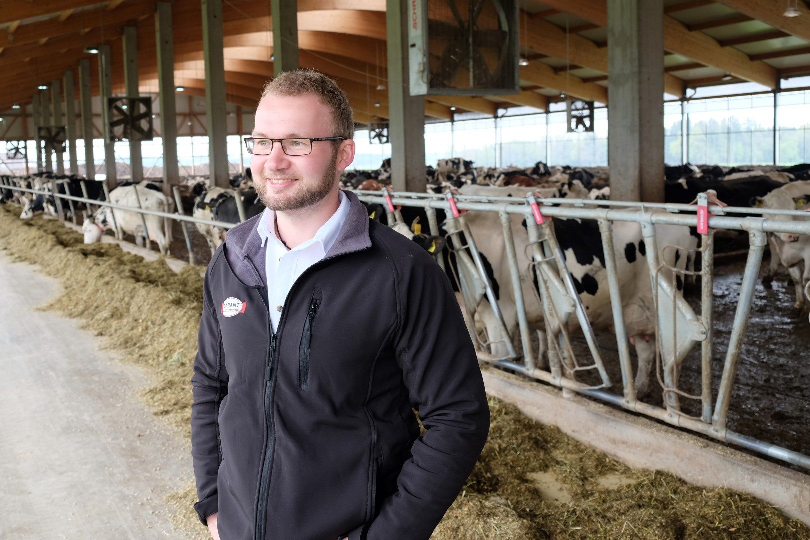 Milchviehexperte Johann Gabauer in einem Stall, im Hintergrund vitale und gesunde Kühe.
